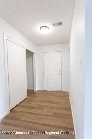 corridor with a textured ceiling and hardwood / wood-style flooring