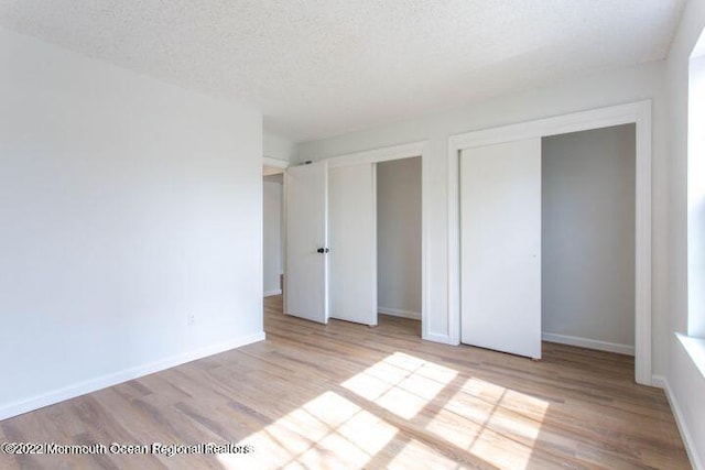 unfurnished bedroom with light hardwood / wood-style floors and a textured ceiling