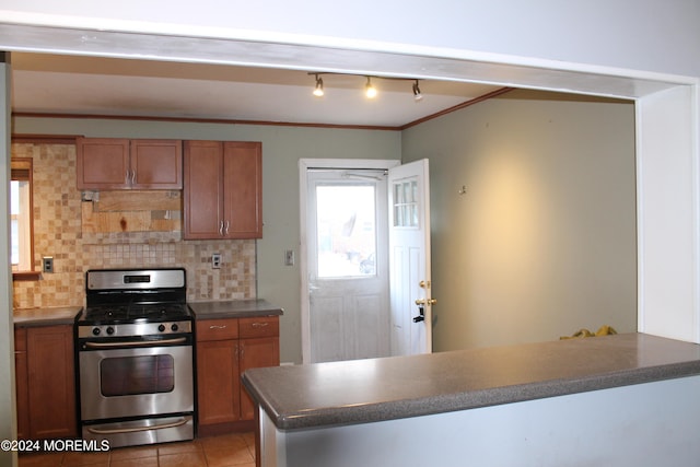 kitchen featuring stainless steel range with gas cooktop, backsplash, kitchen peninsula, light tile patterned floors, and ornamental molding