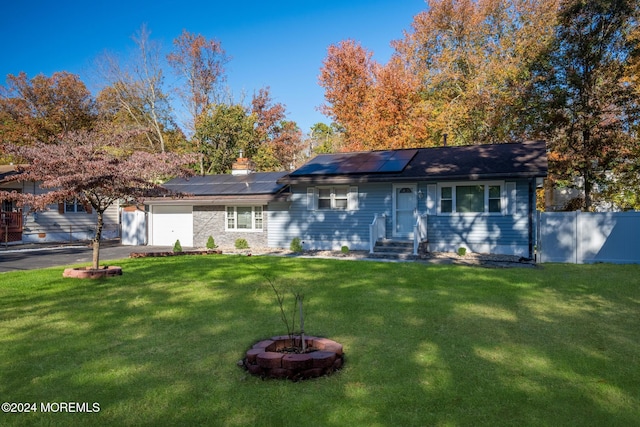 ranch-style home with solar panels, a garage, and a front yard