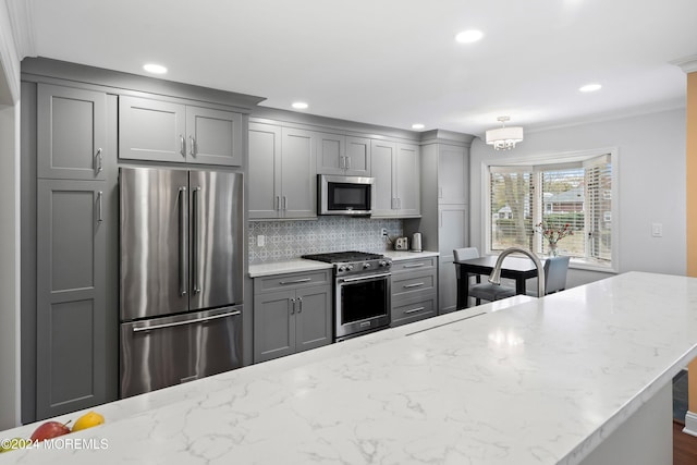 kitchen with tasteful backsplash, gray cabinets, light stone countertops, and appliances with stainless steel finishes