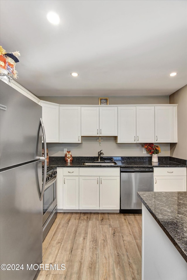 kitchen featuring appliances with stainless steel finishes, light wood-type flooring, white cabinetry, and sink