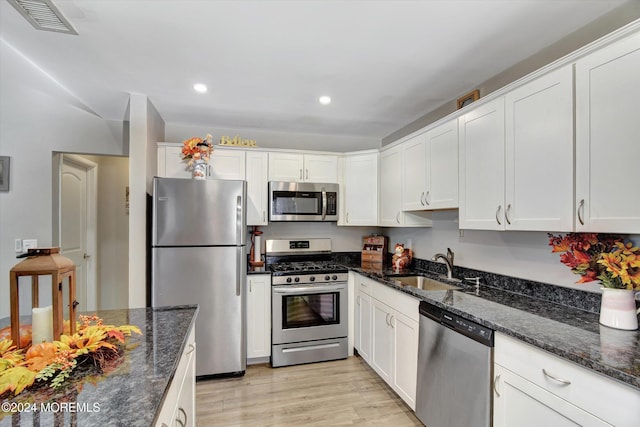1801 Lilly Ln, Jackson, NJ 08527 - kitchen with stainless steel appliances, a sink, white cabinetry, light wood-style floors, and dark stone counters