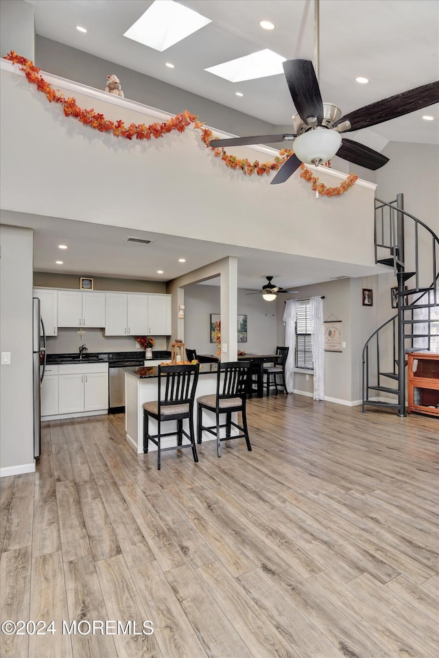 1801 Lilly Ln, Jackson, NJ 08527 - kitchen with dark countertops, appliances with stainless steel finishes, a kitchen bar, a skylight, and light wood-style floors