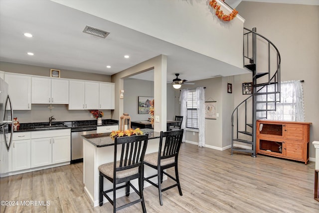 kitchen featuring a kitchen breakfast bar, stainless steel appliances, ceiling fan, light hardwood / wood-style floors, and white cabinetry