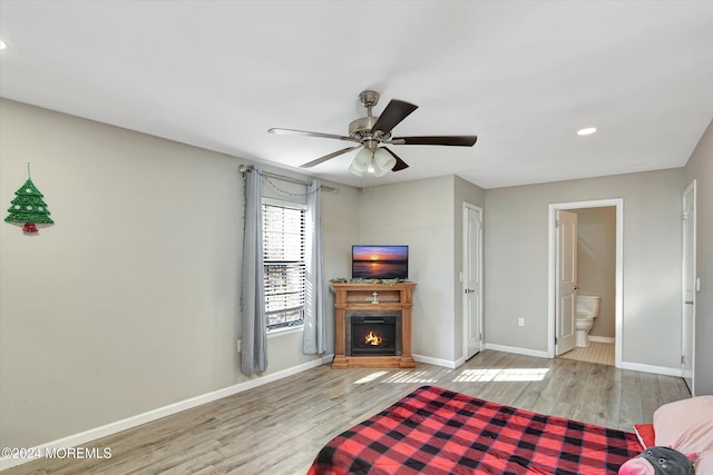 bedroom featuring connected bathroom, ceiling fan, and light wood-type flooring