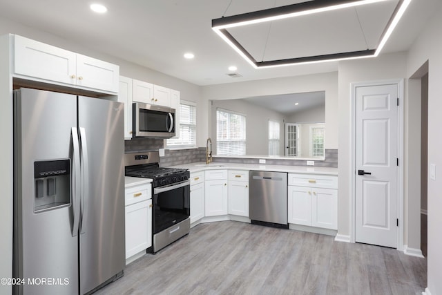 kitchen featuring sink, tasteful backsplash, light hardwood / wood-style floors, white cabinets, and appliances with stainless steel finishes