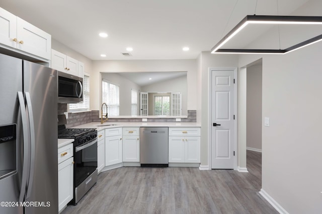 kitchen with white cabinetry, sink, stainless steel appliances, light hardwood / wood-style flooring, and decorative backsplash