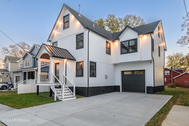 modern farmhouse featuring a lawn, a porch, and a garage