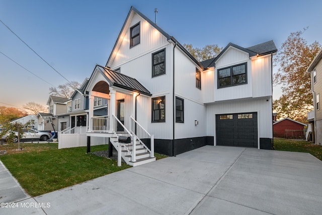 modern inspired farmhouse with covered porch, a yard, and a garage