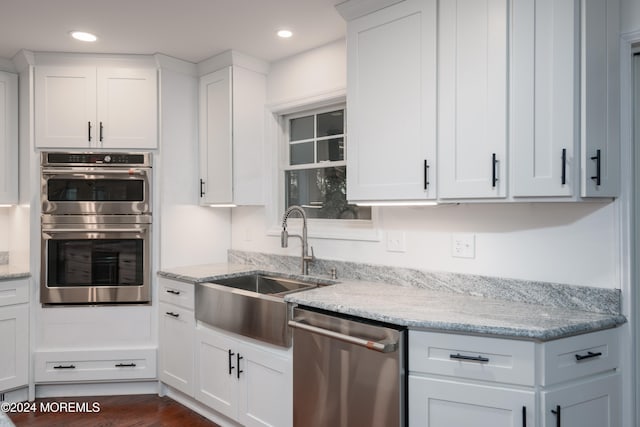 kitchen with light stone countertops, sink, stainless steel appliances, dark hardwood / wood-style flooring, and white cabinets