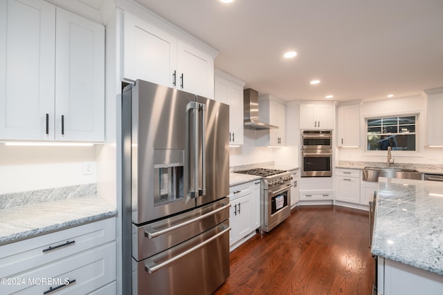 kitchen featuring light stone countertops, wall chimney exhaust hood, sink, high quality appliances, and white cabinetry