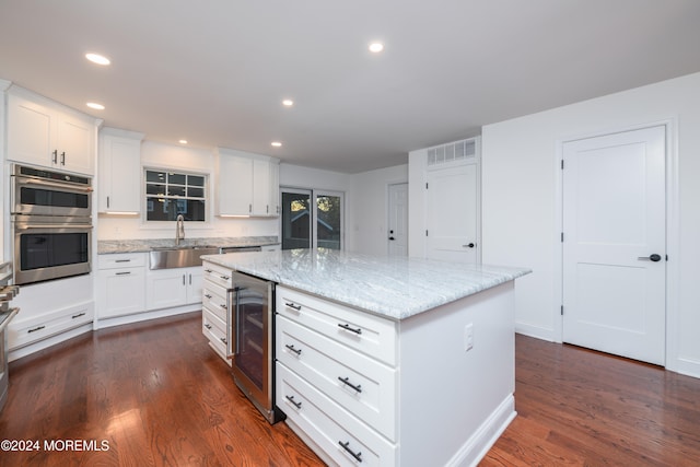 kitchen featuring white cabinets, a center island, dark hardwood / wood-style floors, and beverage cooler