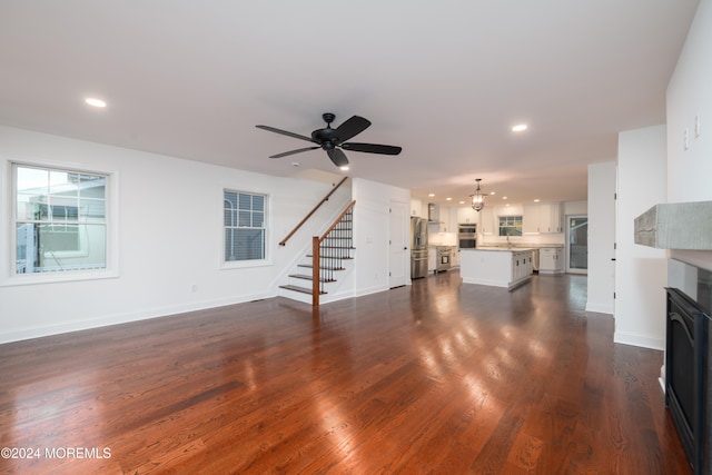 unfurnished living room with ceiling fan with notable chandelier and dark hardwood / wood-style floors