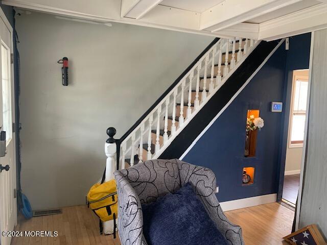 staircase featuring beam ceiling and hardwood / wood-style flooring