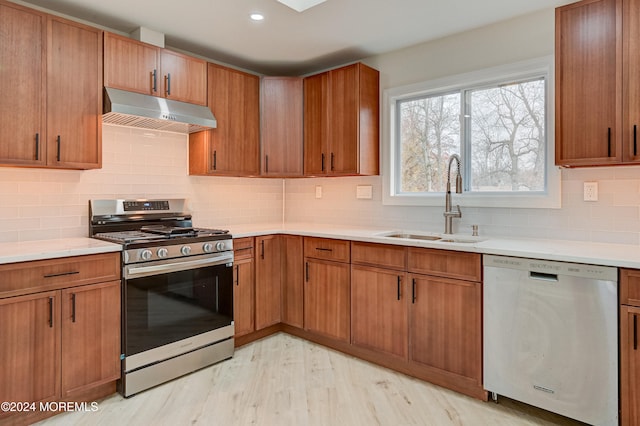 kitchen with tasteful backsplash, sink, light hardwood / wood-style floors, and appliances with stainless steel finishes