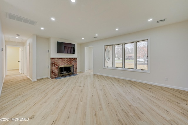 unfurnished living room featuring light hardwood / wood-style floors and a brick fireplace