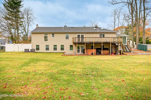 rear view of property featuring a wooden deck, a yard, and central AC unit