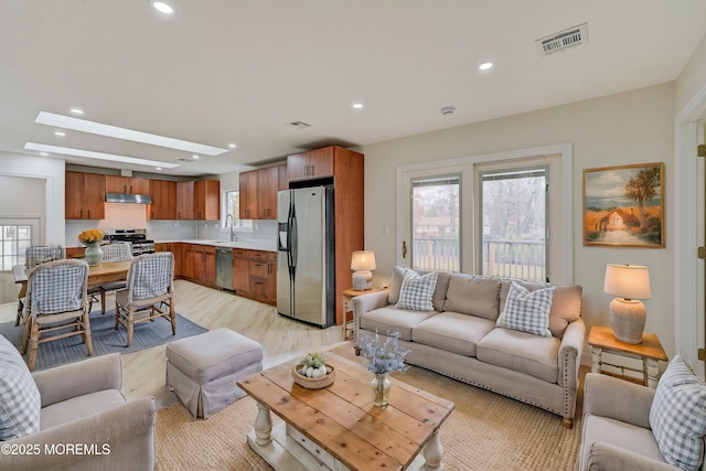 living room with light wood-type flooring, sink, and a skylight