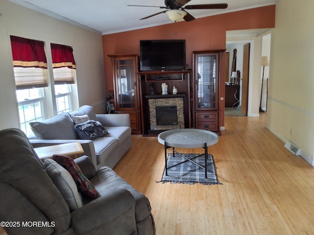 32 Village Rd, Morganville, NJ 07751 - living room with wood finished floors, a stone fireplace, ceiling fan, ornamental molding, and visible vents