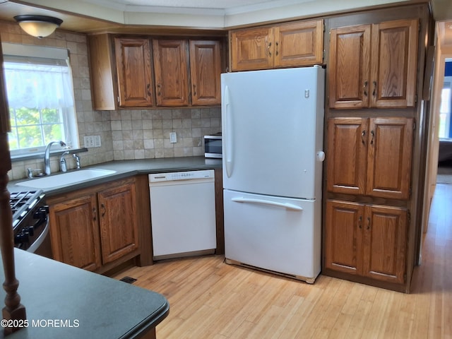 32 Village Rd, Morganville, NJ 07751 - kitchen featuring tasteful backsplash, a sink, brown cabinetry, light wood-type flooring, and stainless steel appliances