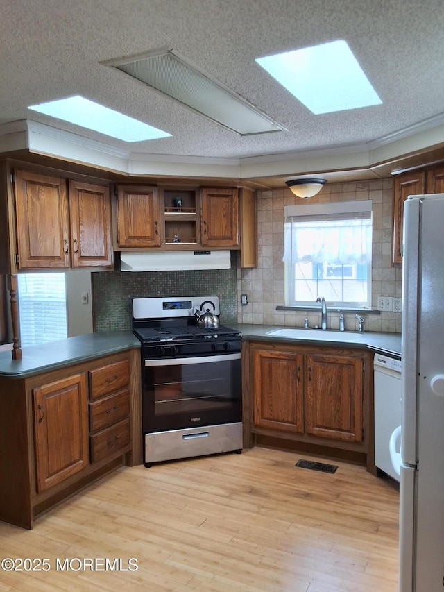 32 Village Rd, Morganville, NJ 07751 - kitchen featuring brown cabinets, under cabinet range hood, backsplash, a sink, and white appliances