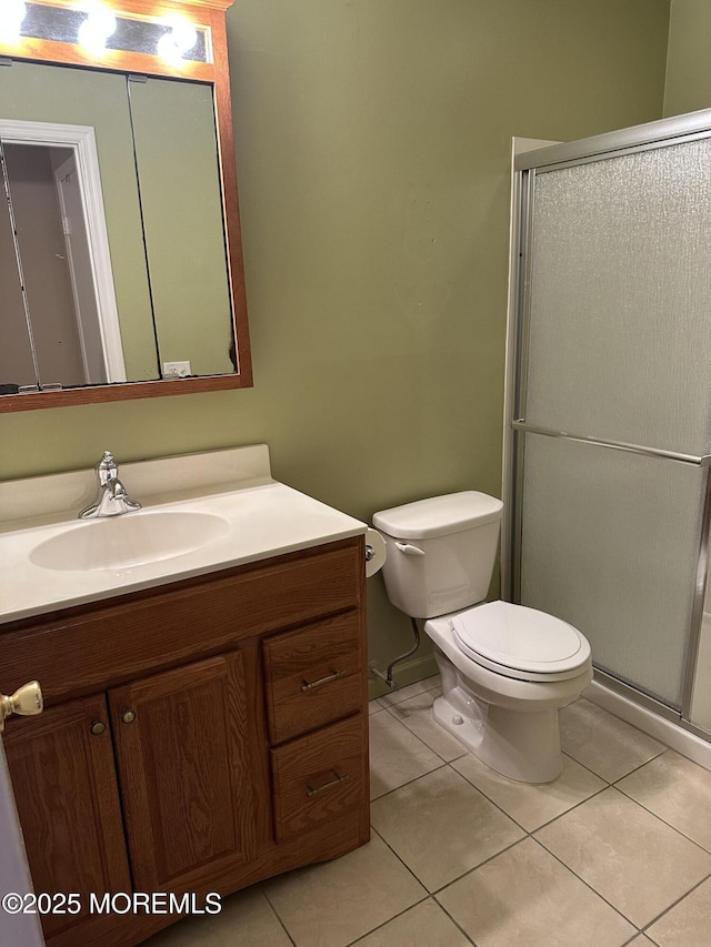 bathroom with toilet, tile patterned flooring, vanity, and walk in shower