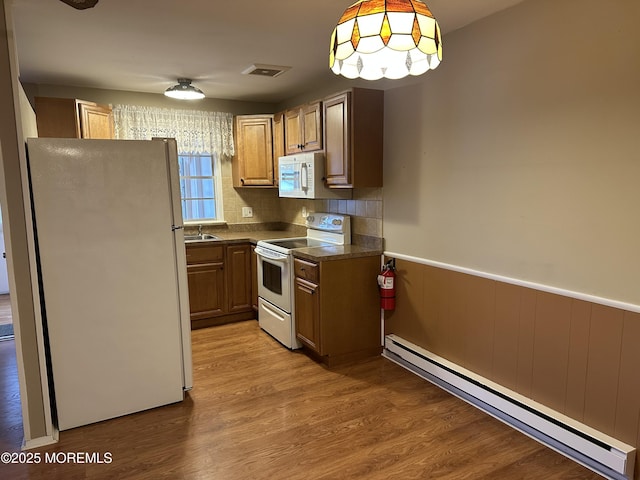 kitchen with tasteful backsplash, a baseboard heating unit, pendant lighting, light hardwood / wood-style floors, and white appliances