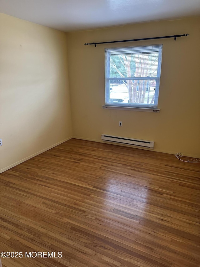 spare room with hardwood / wood-style flooring and a baseboard heating unit