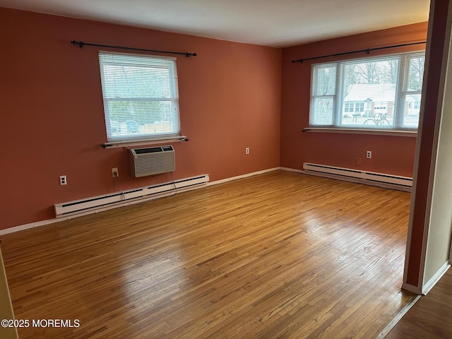 spare room featuring a wall mounted air conditioner, wood-type flooring, and a baseboard heating unit