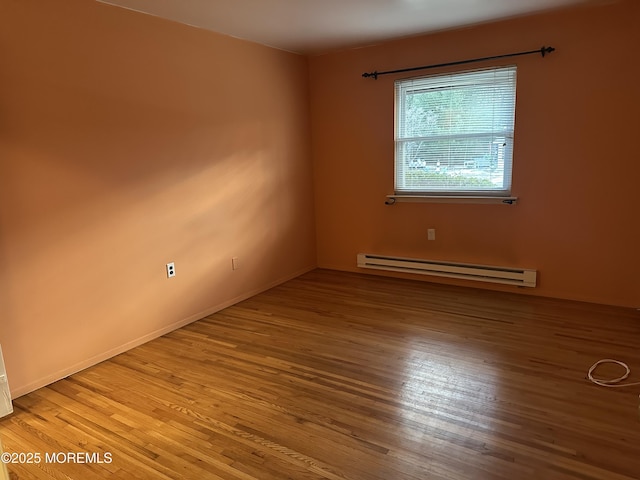 unfurnished room featuring wood-type flooring and baseboard heating