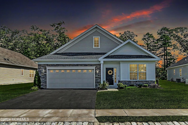 view of front of property featuring a garage, concrete driveway, stone siding, cooling unit, and a front yard