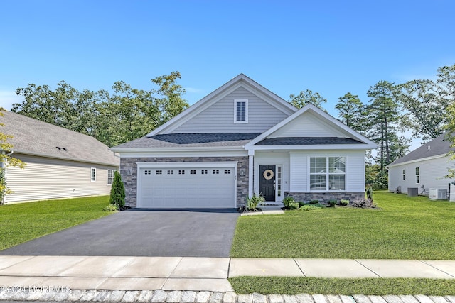 view of front of house featuring central AC unit, stone siding, aphalt driveway, an attached garage, and a front yard