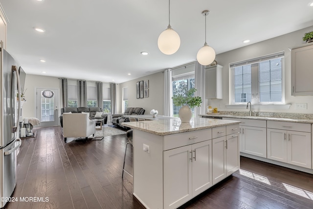 kitchen with dark wood finished floors, open floor plan, a center island, decorative light fixtures, and freestanding refrigerator