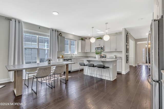 kitchen with a kitchen breakfast bar, stainless steel appliances, dark wood finished floors, and a center island