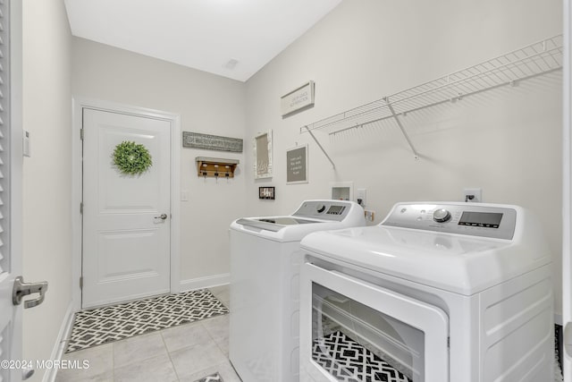 washroom with laundry area, light tile patterned flooring, independent washer and dryer, and baseboards