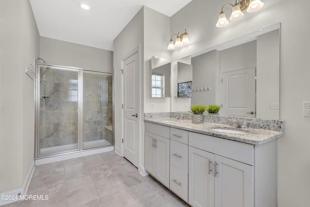 full bath featuring a sink, a shower stall, baseboards, and double vanity