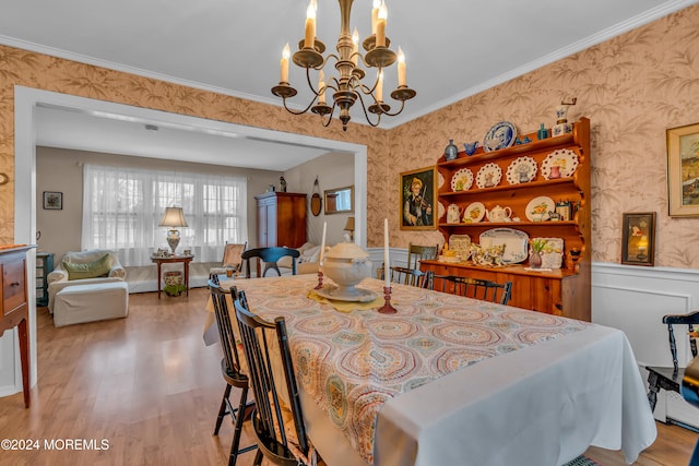 dining room with light hardwood / wood-style floors, ornamental molding, and an inviting chandelier