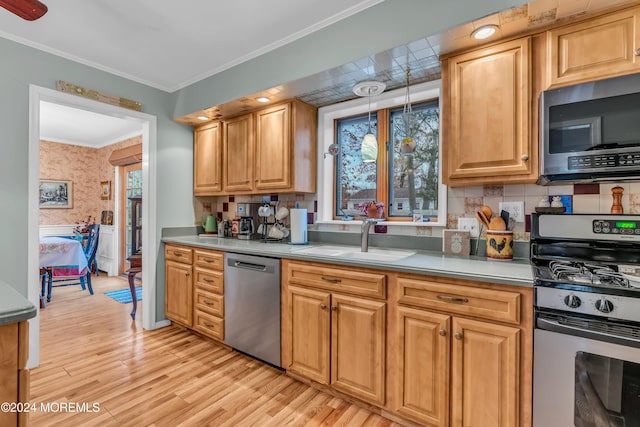 kitchen featuring stainless steel appliances, crown molding, sink, pendant lighting, and light hardwood / wood-style floors