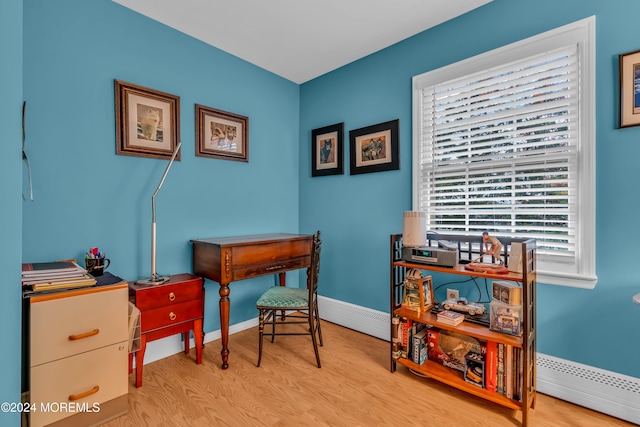 office area with light wood-type flooring, a baseboard radiator, and a healthy amount of sunlight