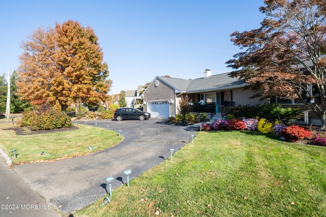 view of front of house featuring covered porch, a garage, and a front lawn