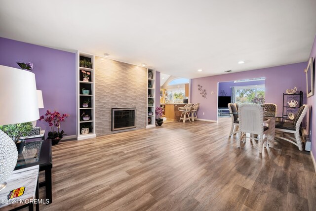 living room featuring hardwood / wood-style flooring, a large fireplace, and built in features