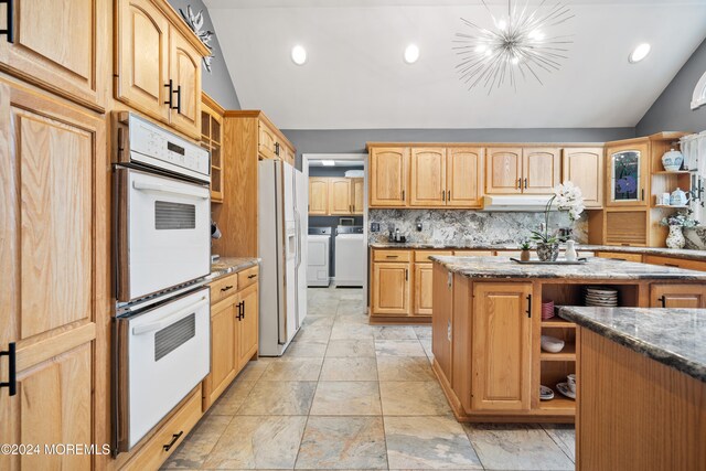 kitchen featuring washing machine and dryer, a chandelier, white appliances, lofted ceiling, and a kitchen island