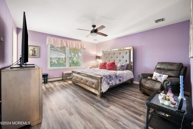 bedroom with hardwood / wood-style flooring, ceiling fan, and a baseboard heating unit