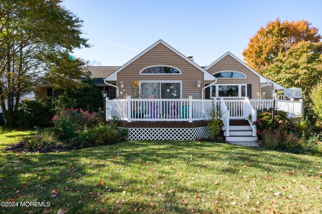 rear view of house featuring a lawn and a deck