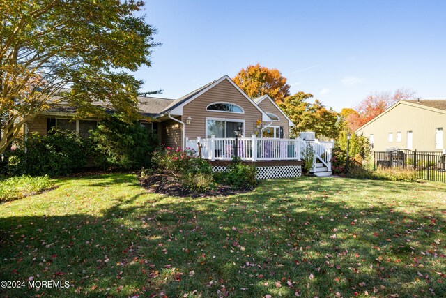 rear view of property with a wooden deck and a yard