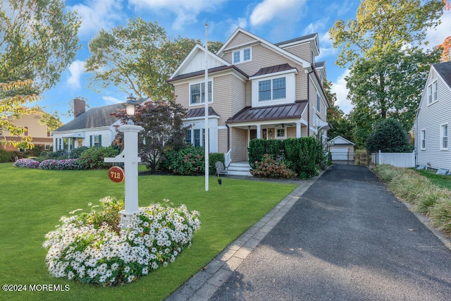 view of front of house featuring a front yard, a porch, a garage, and an outdoor structure