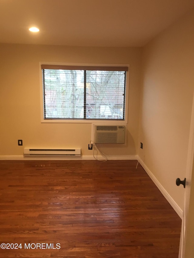 spare room with a wall mounted air conditioner, dark hardwood / wood-style flooring, baseboard heating, and a healthy amount of sunlight