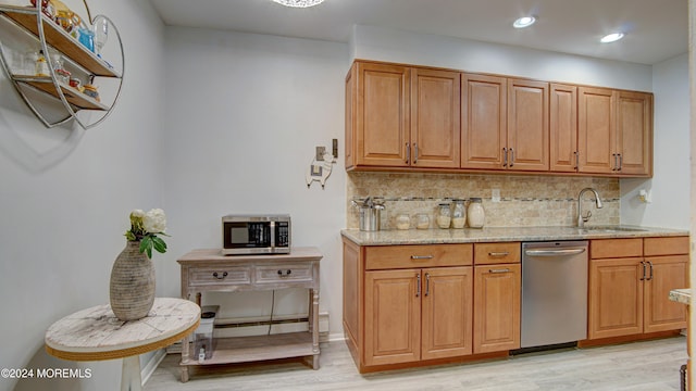 kitchen with sink, stainless steel appliances, tasteful backsplash, light stone counters, and light wood-type flooring