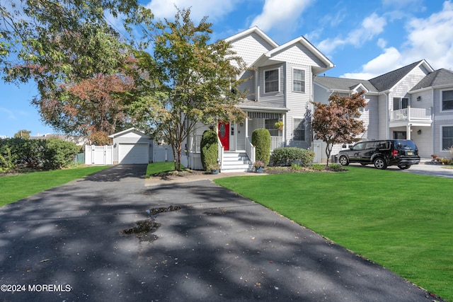 view of front of property featuring a porch, a garage, an outdoor structure, and a front lawn